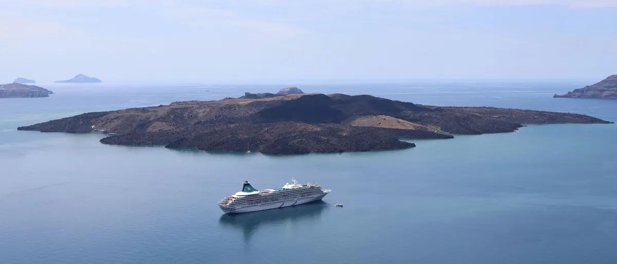 Cruise ship anchored off the volcanic island of Nea Kameni near Santorini, Greece
