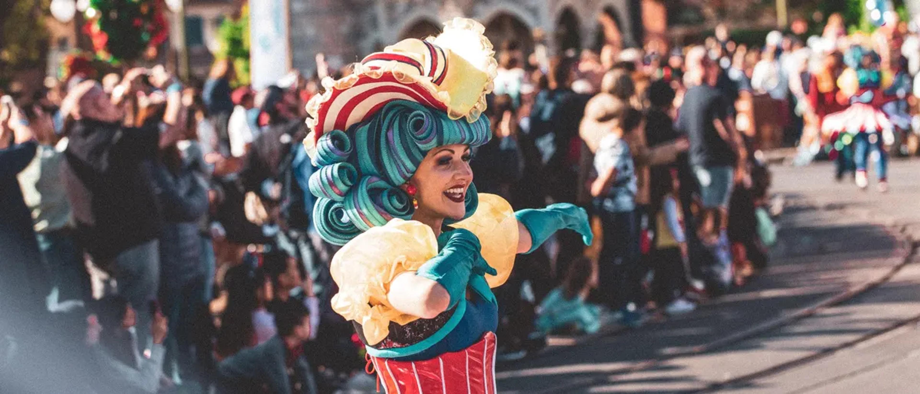 Costumed carnival performer leading a crowd at an outdoor Halloween street party