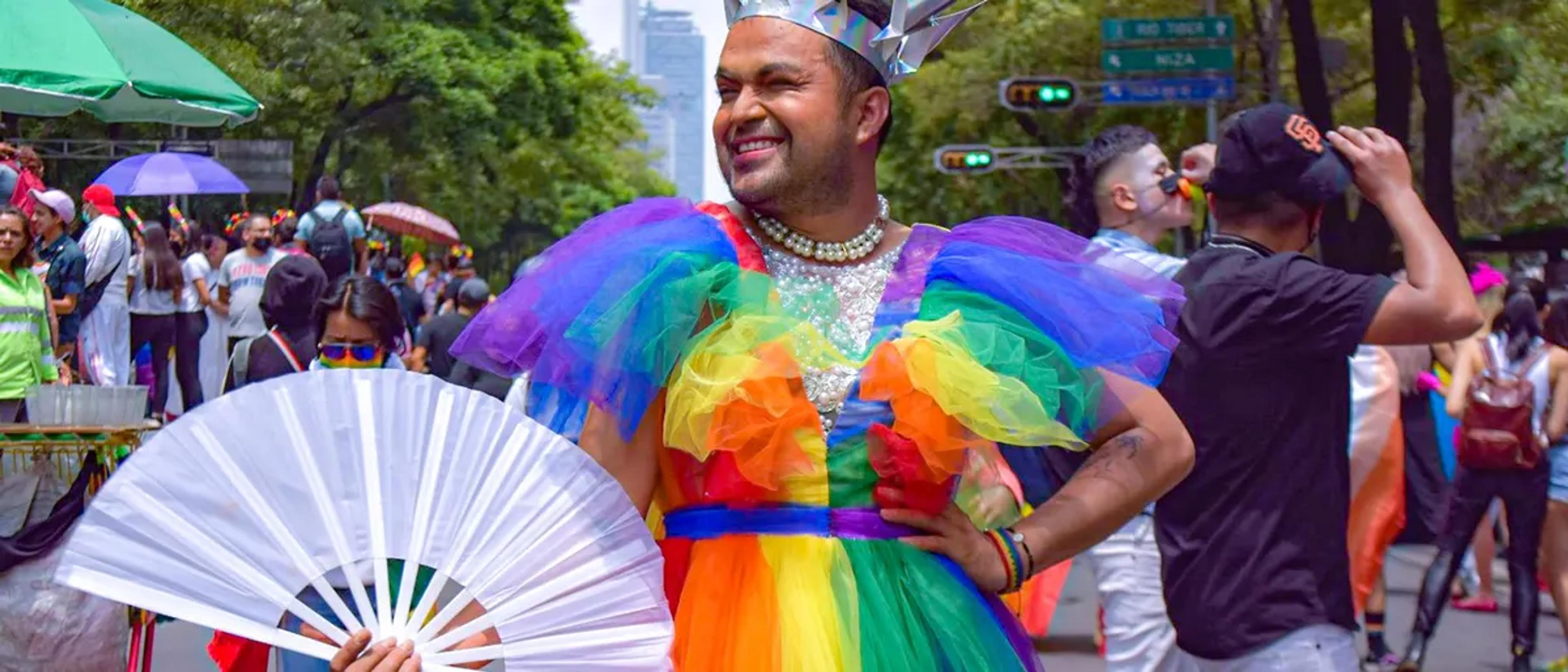A smiling reveler in a rainbow tulle dress and crown at the Mexico City Pride march