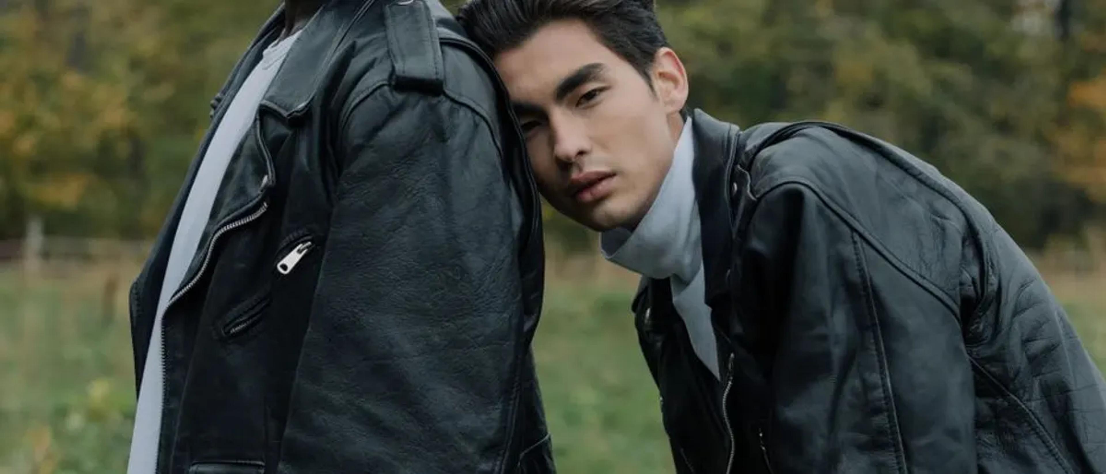 Two men in black leather jackets standing close together outdoors
