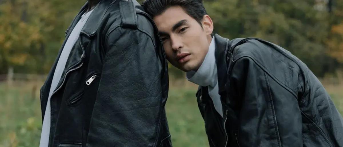 Two men in black leather jackets standing close together outdoors