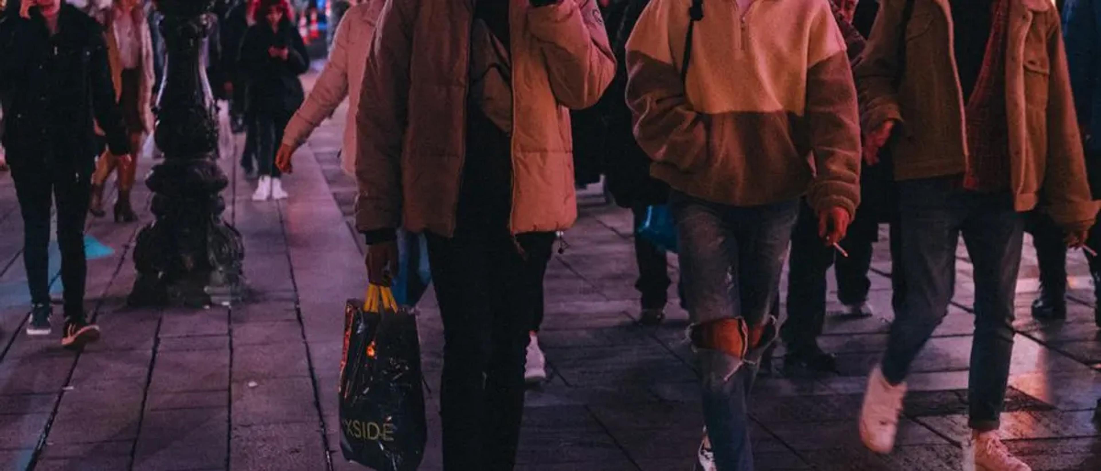 Crowd of people walking a neon-lit city street on a night out