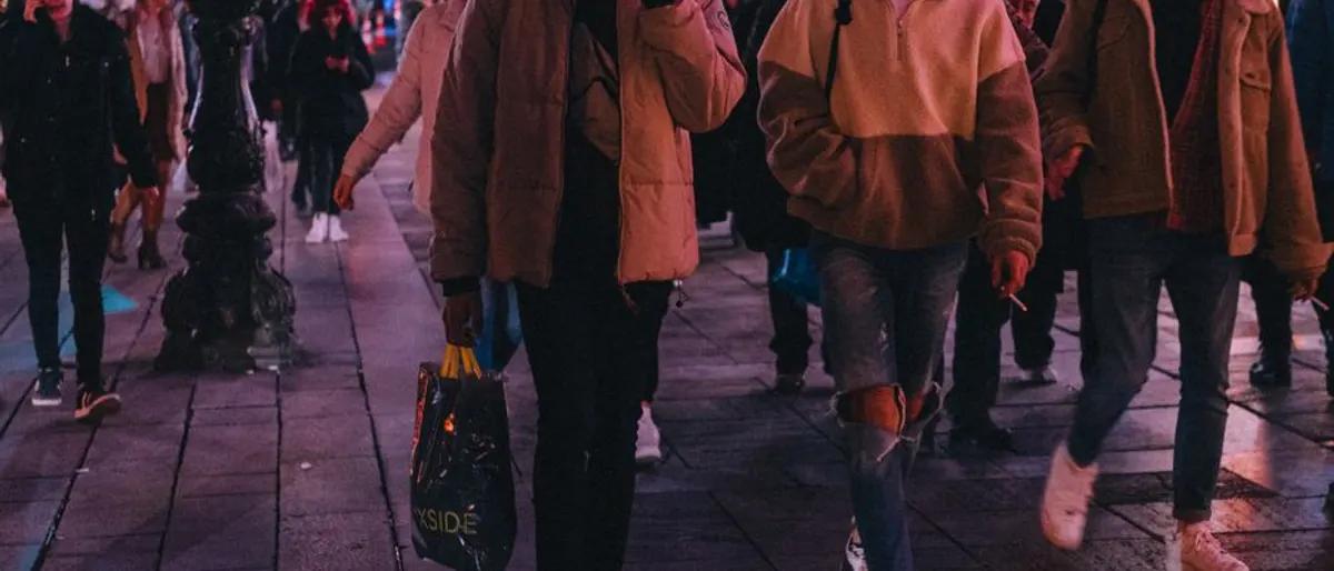 Crowd of people walking a neon-lit city street on a night out