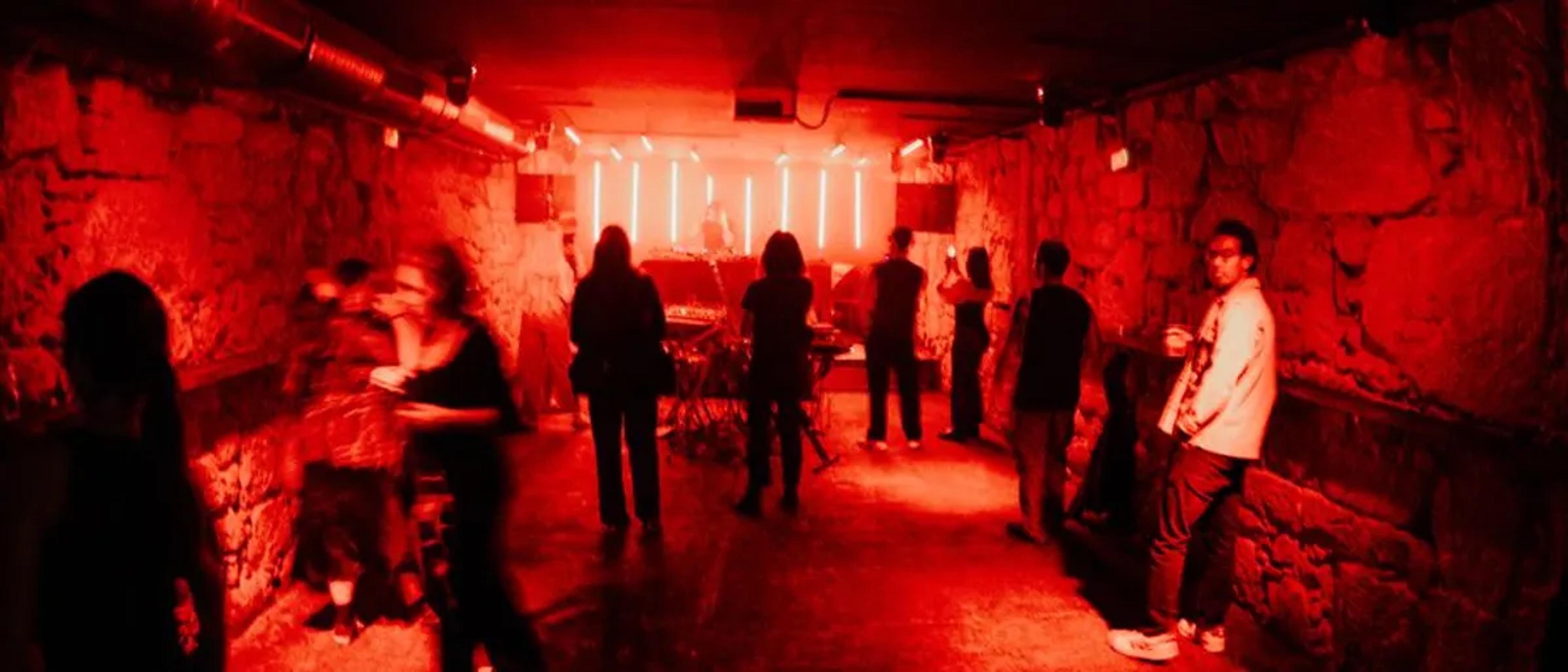 People gathered in a dim red-lit underground club room