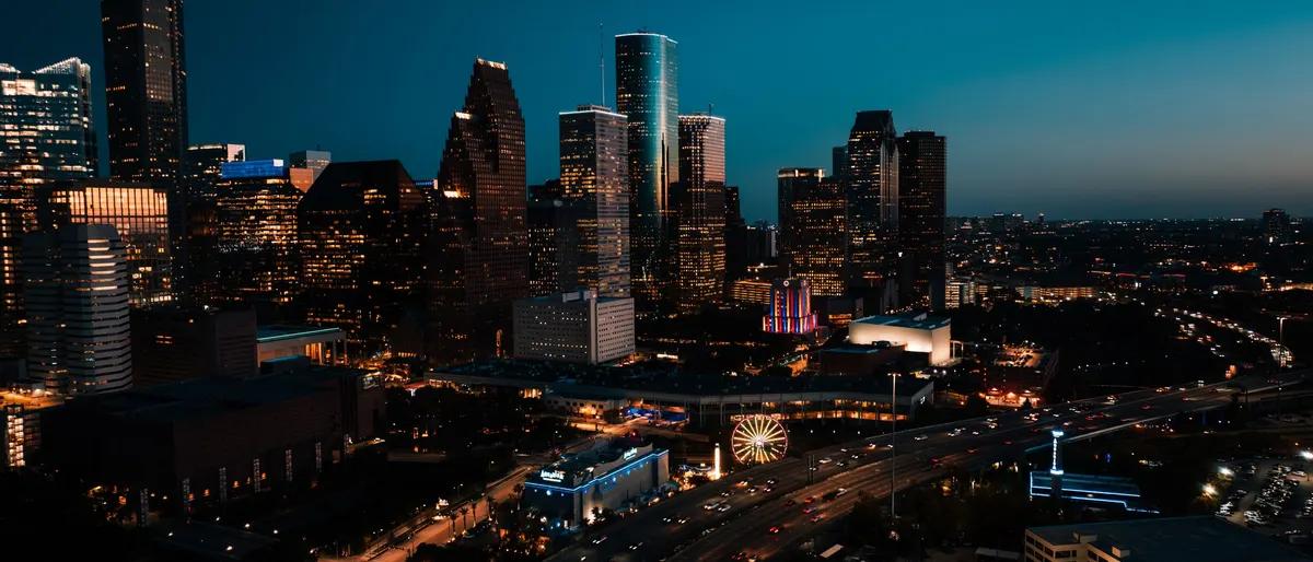 Downtown Houston skyline lit up at dusk above the freeway
