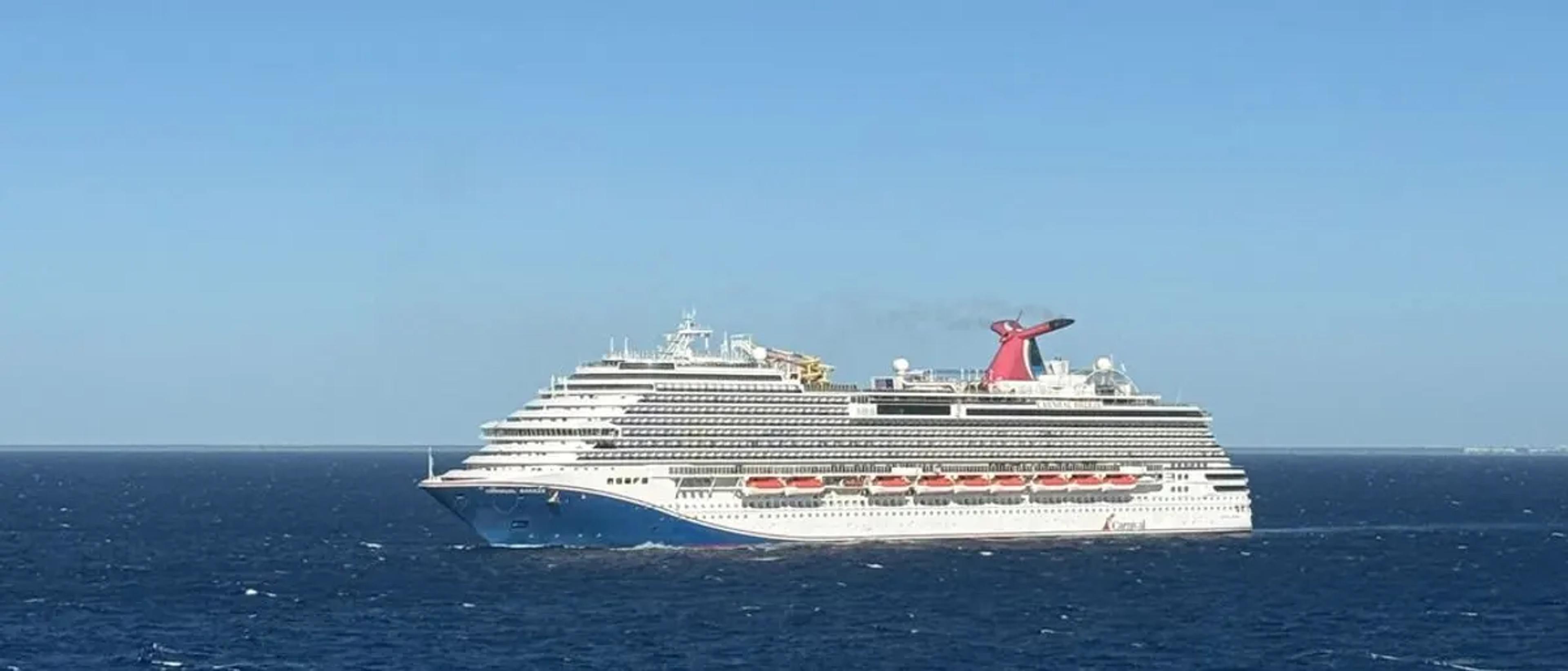 Large cruise ship sailing across open blue ocean under a clear sky