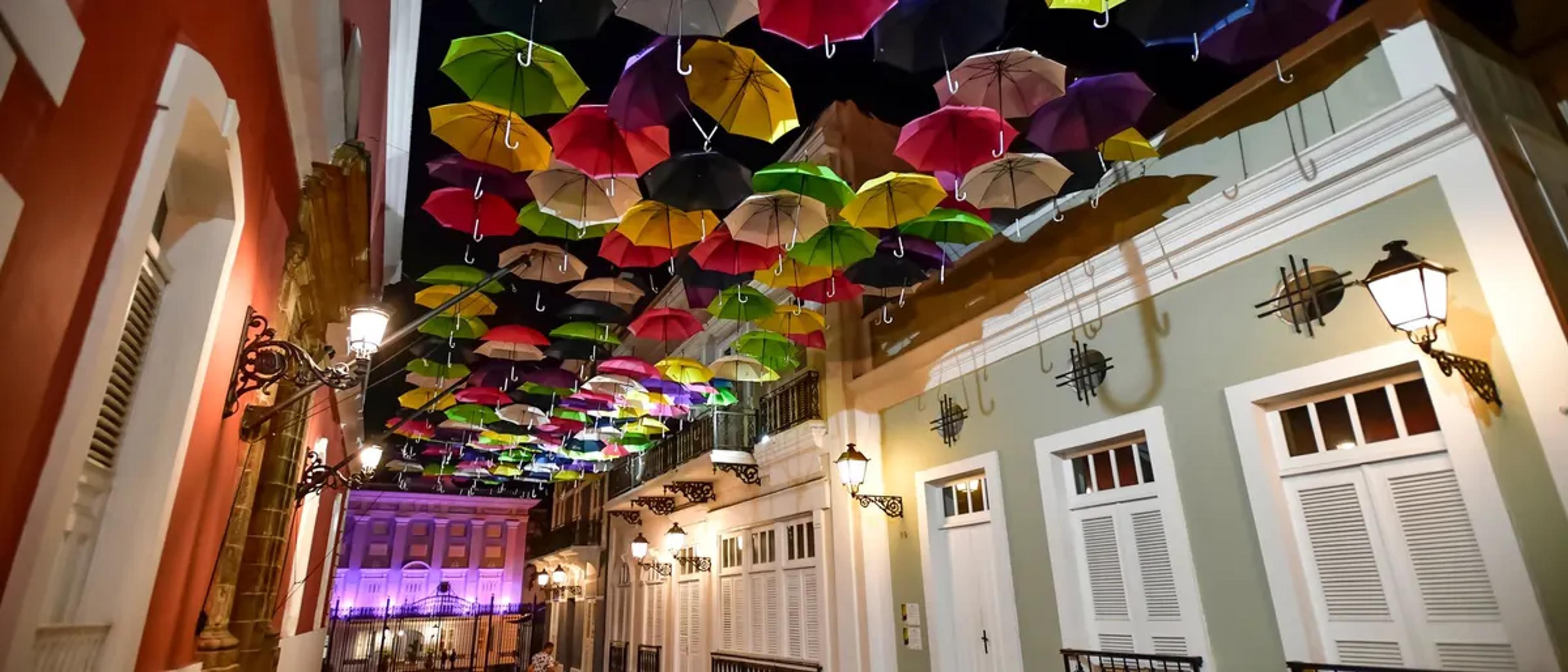 Colorful umbrellas strung above Calle La Fortaleza in Old San Juan, lit at night