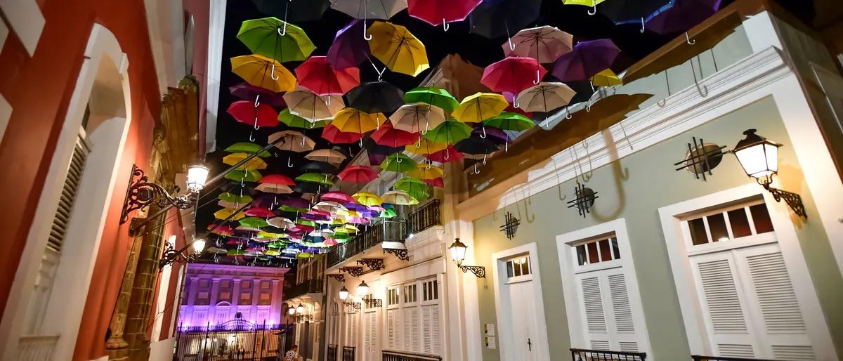 Colorful umbrellas strung above Calle La Fortaleza in Old San Juan, lit at night