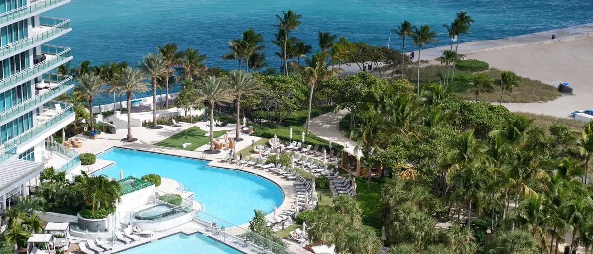 A Florida resort pool deck among palm trees beside the beach and turquoise water