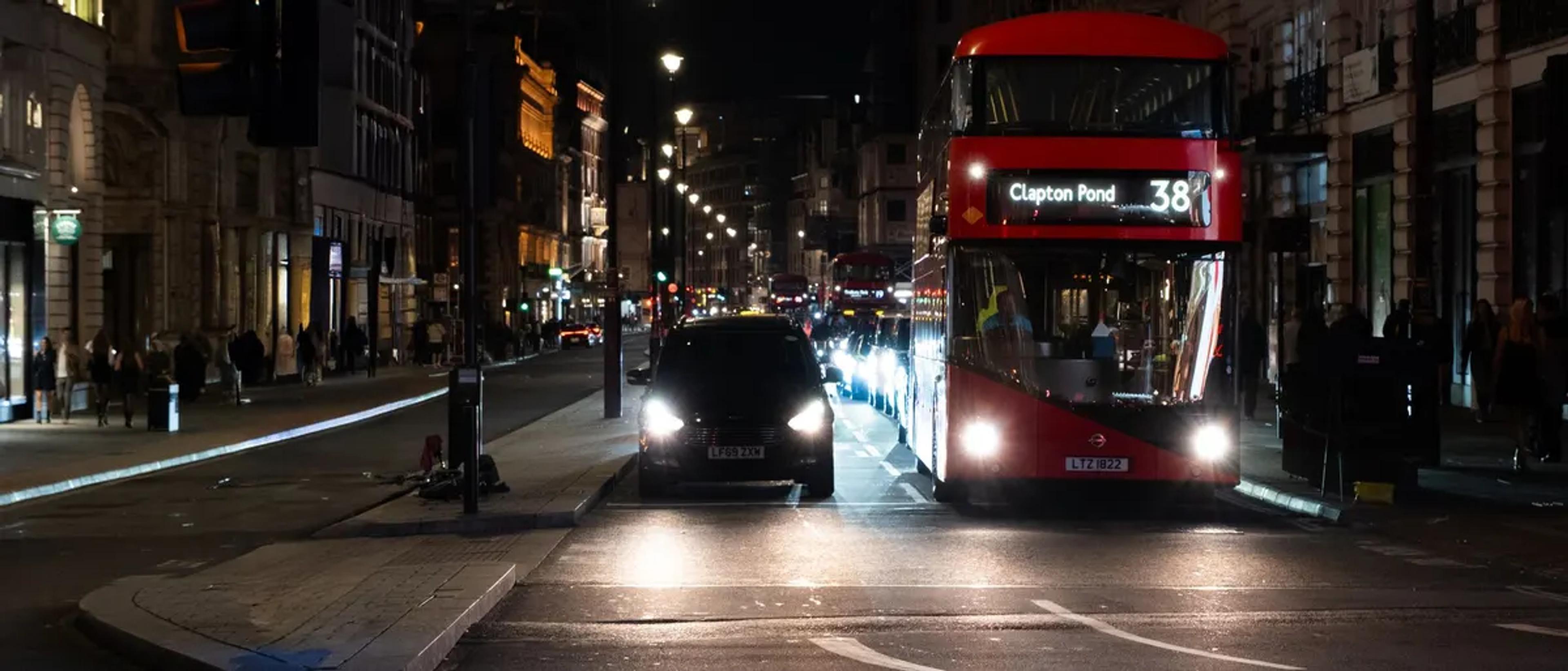 A red route 38 double-decker bus on a central London street at night