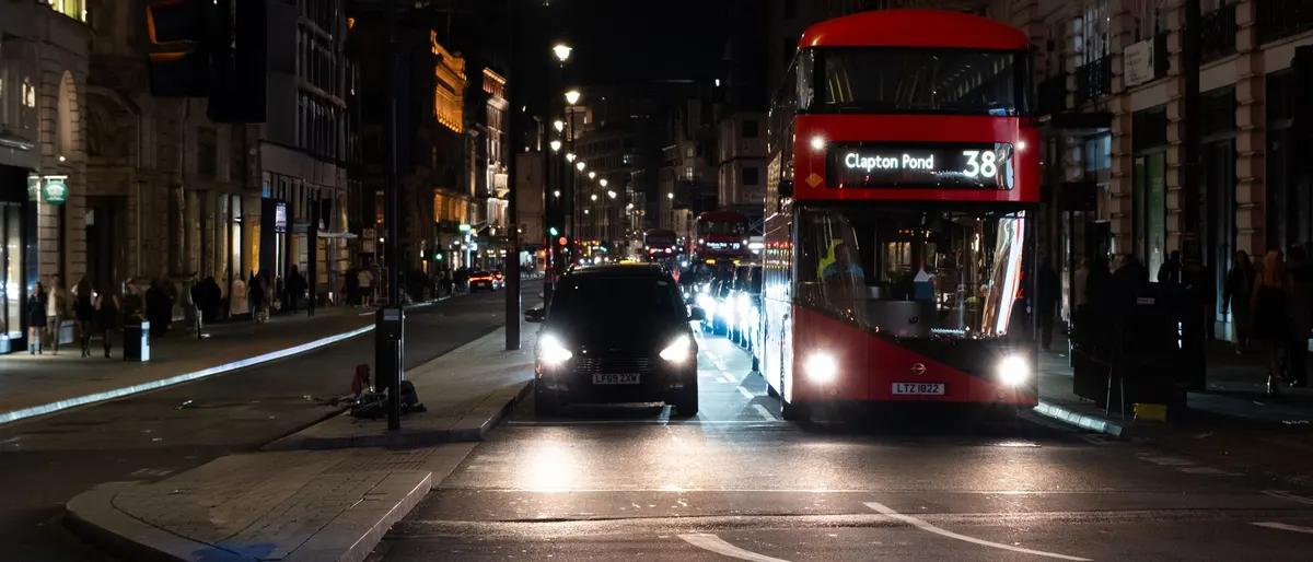 A red route 38 double-decker bus on a central London street at night