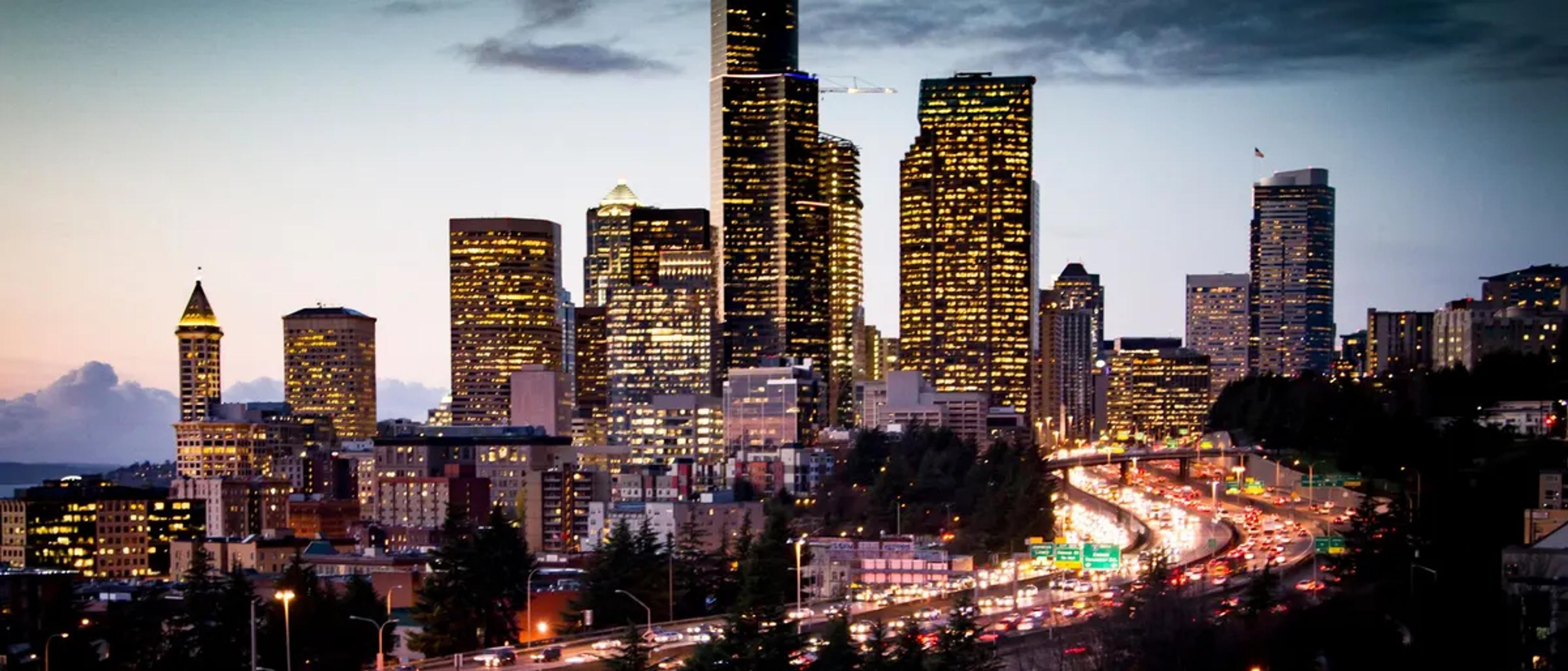 Downtown Seattle skyline lit up at dusk above the freeway