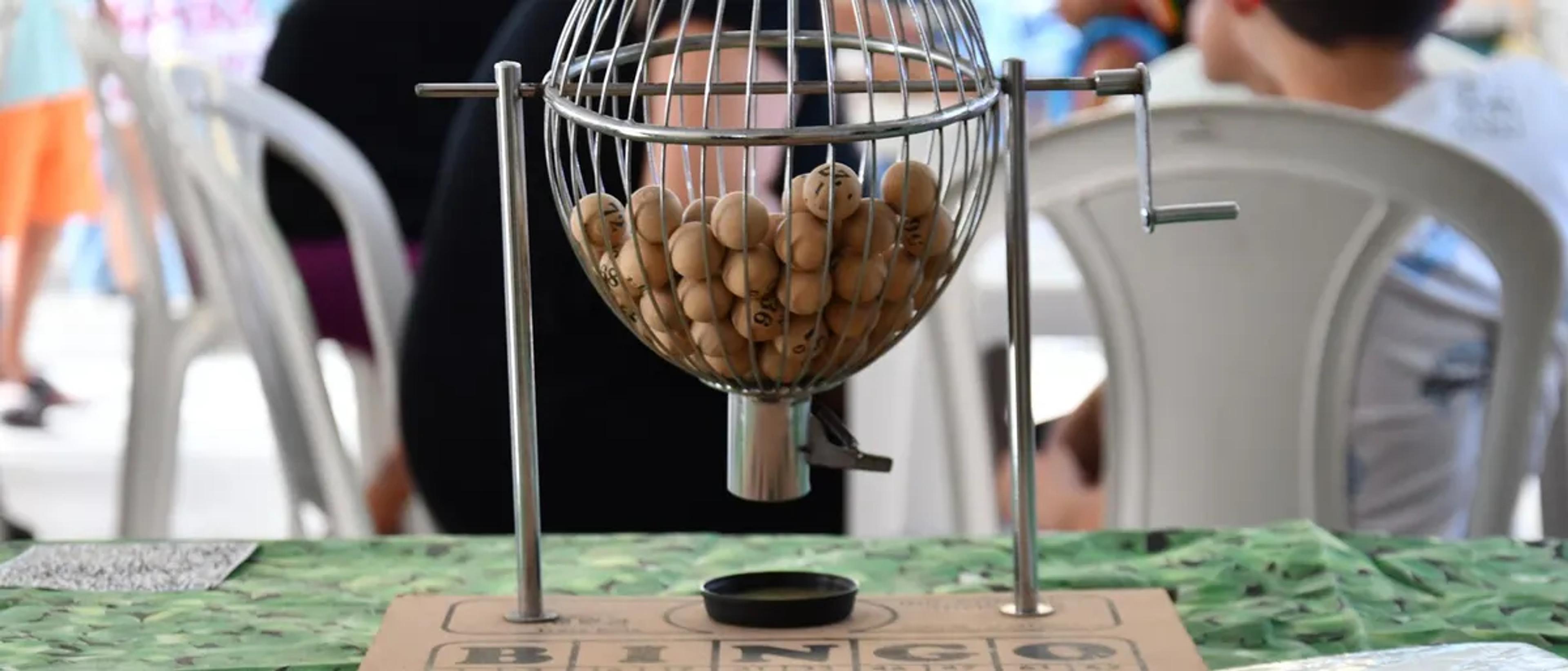 Bingo cage filled with numbered balls on a table marked BINGO