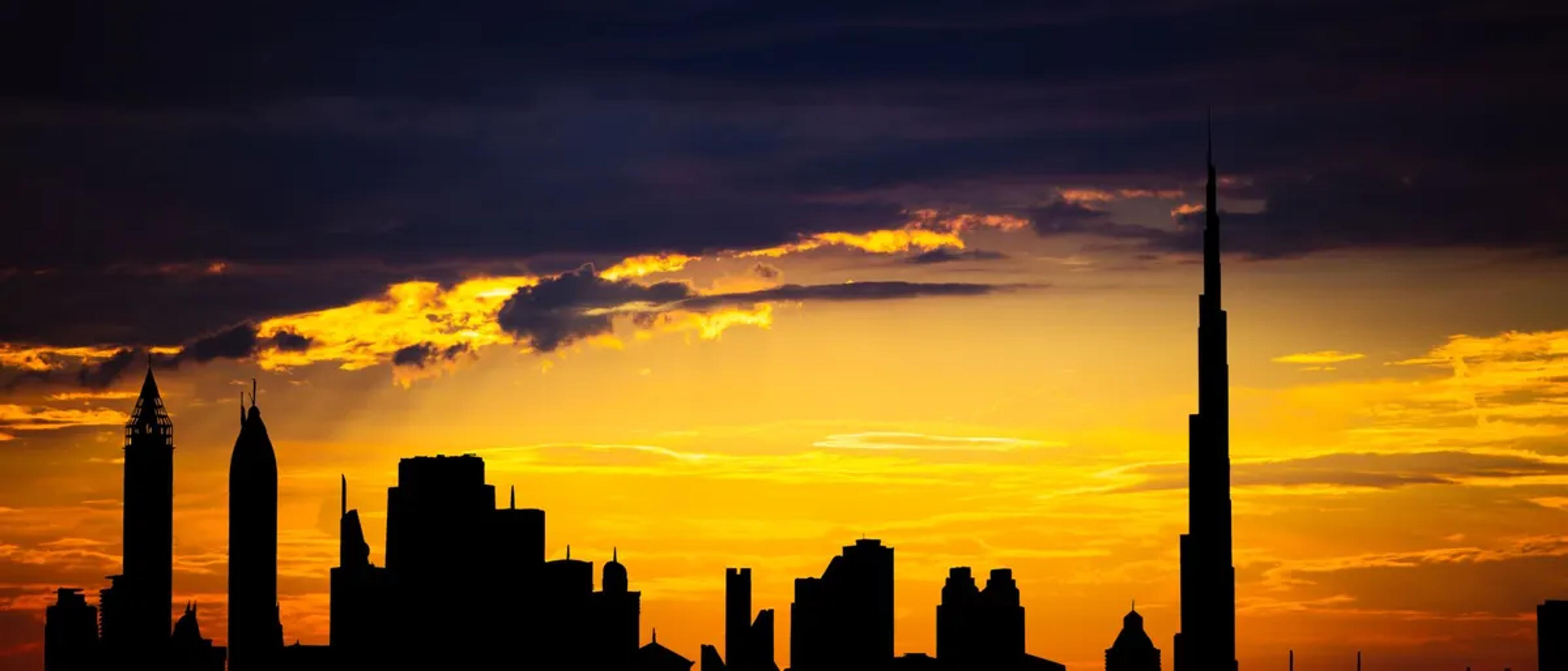 Dubai skyline and the Burj Khalifa in silhouette at sunset
