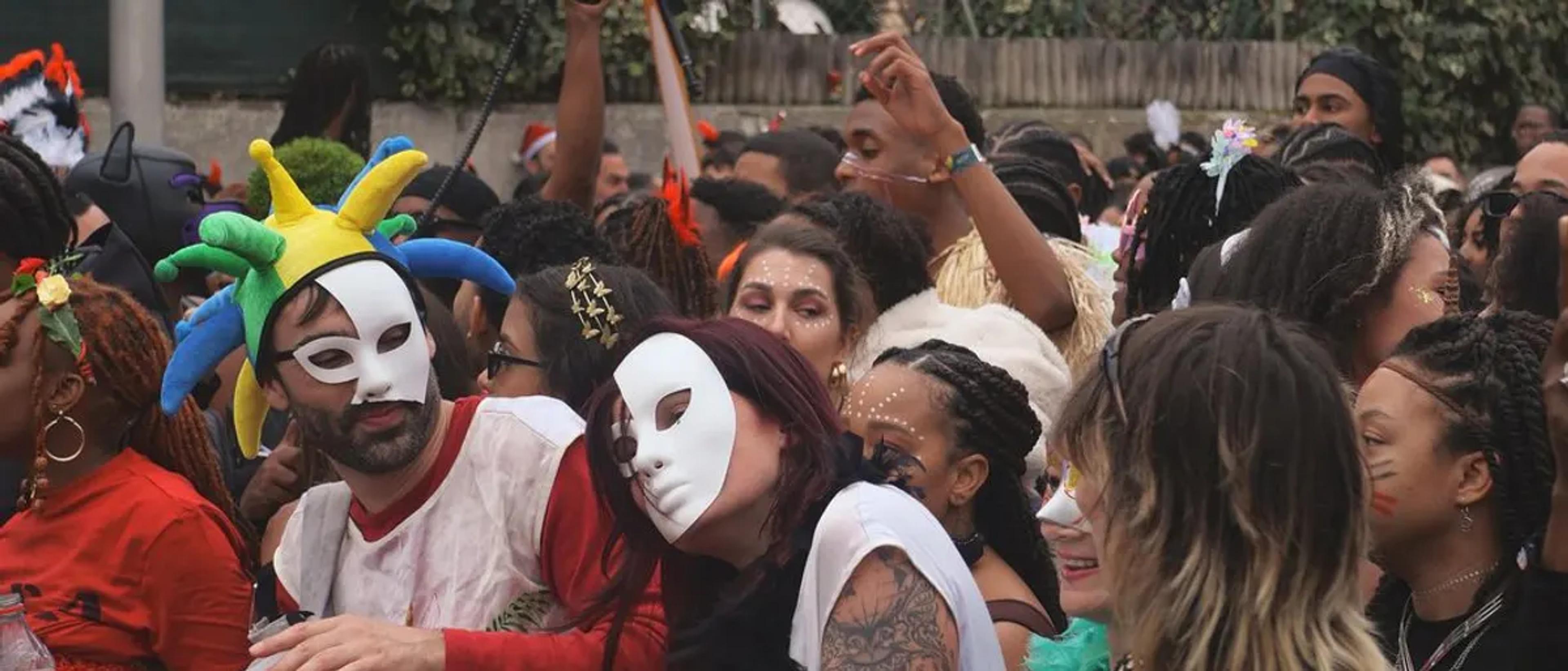Dense crowd of people in masks and costumes at a Halloween street celebration