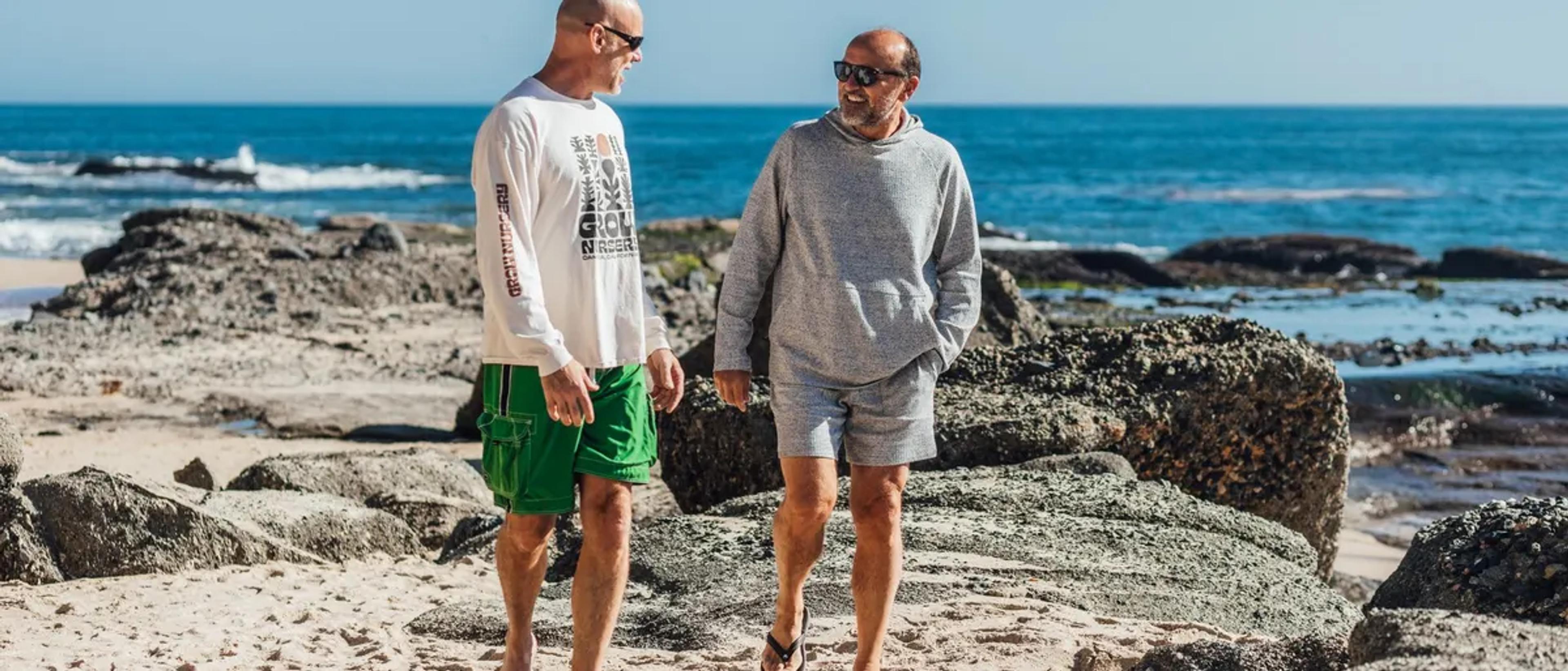Two men walking along a sunny beach on vacation