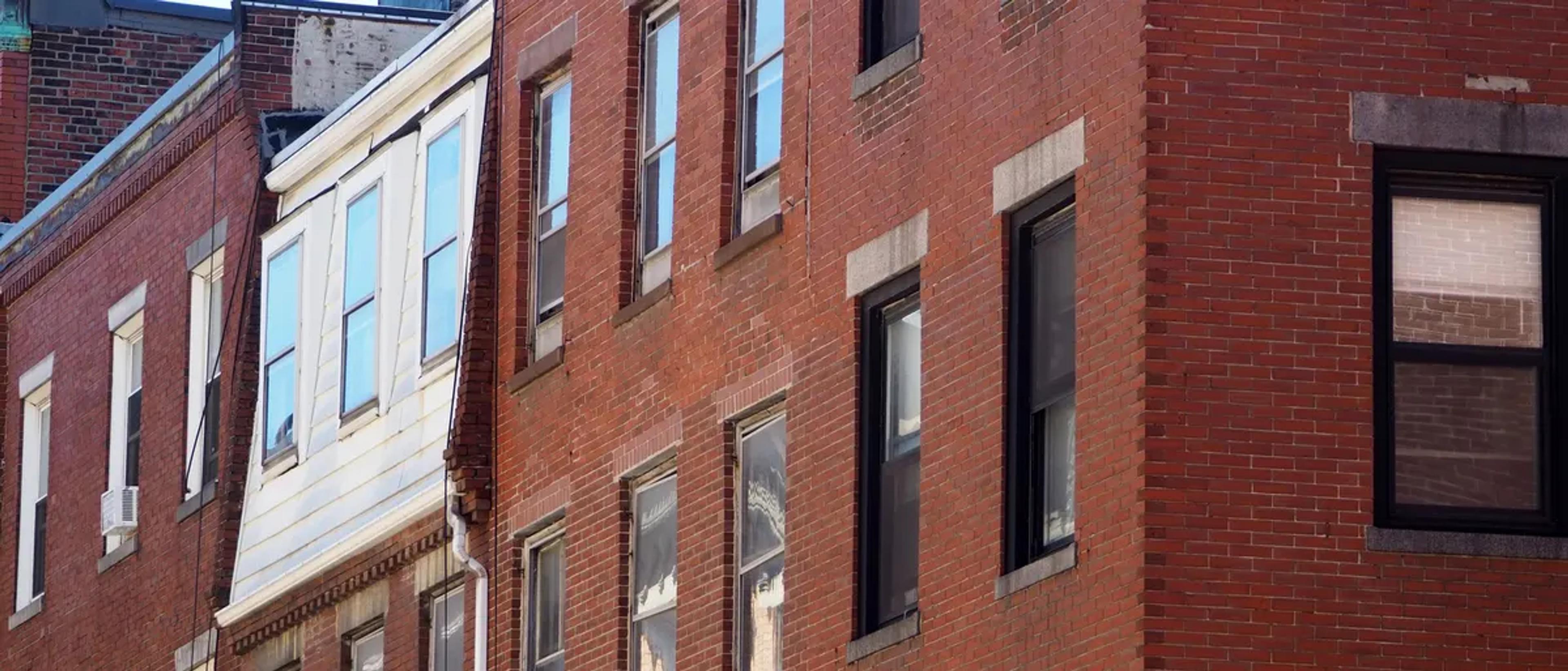 Red brick rowhouses with tall windows on a Boston street