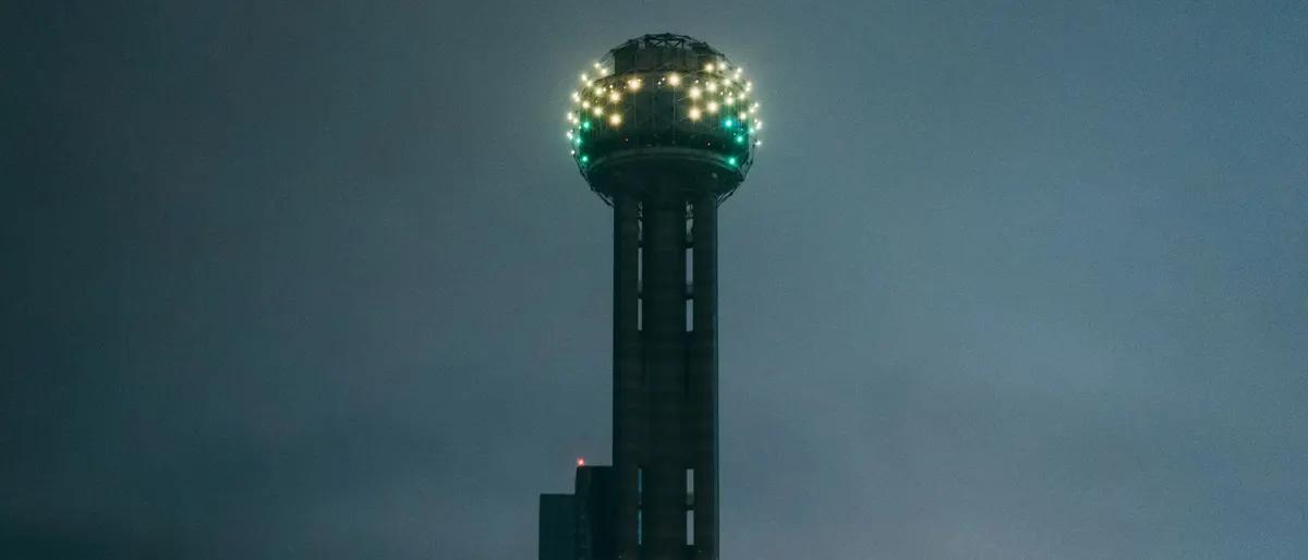 Reunion Tower lit up at night in downtown Dallas, next to the Hyatt Regency that hosts Texas Bear Round-Up