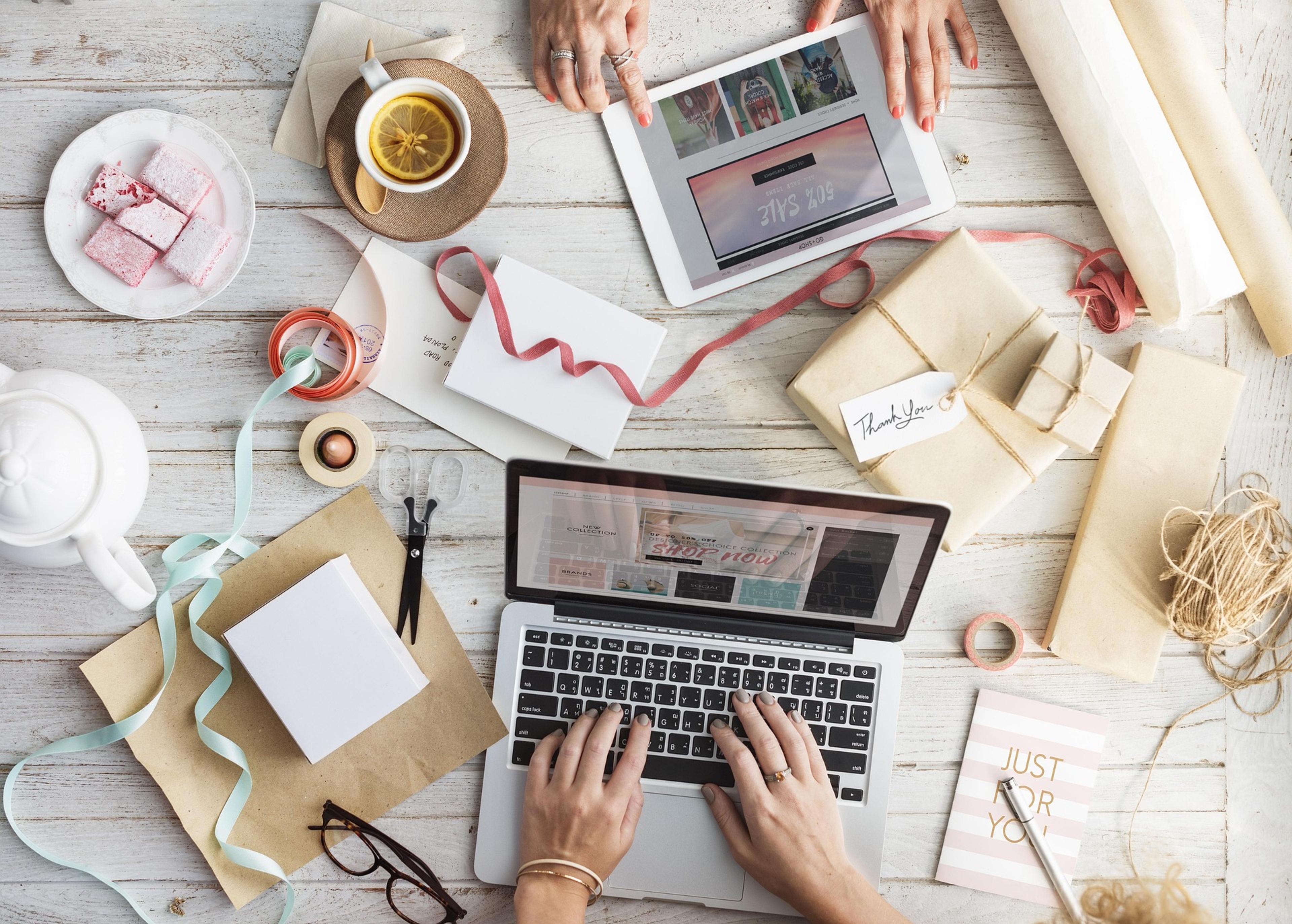 Twee mensen plannen een bruiloft aan tafel met laptops, kaarten en lint