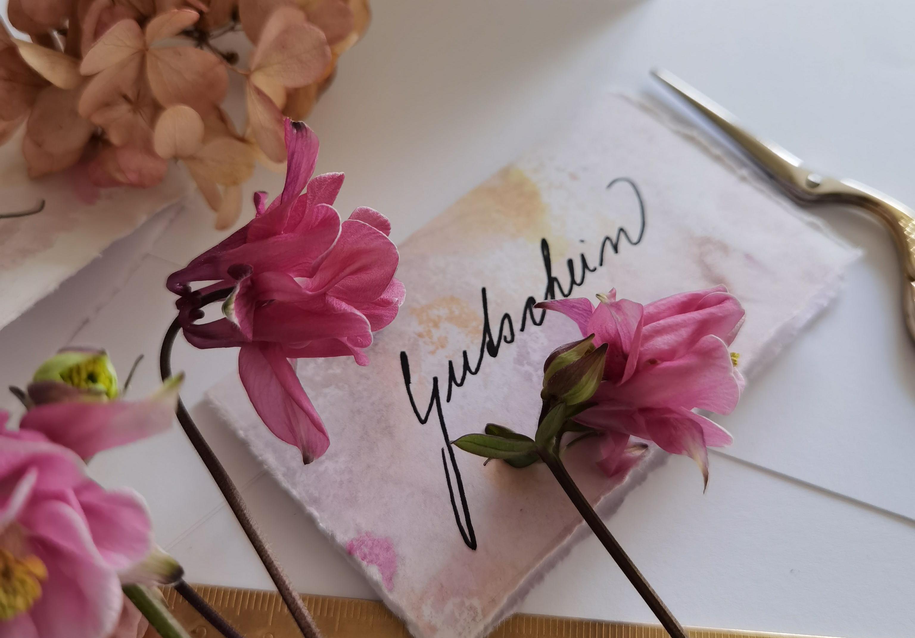 Handgeschreven naamkaartjes met bloemen, een schaar en een liniaal