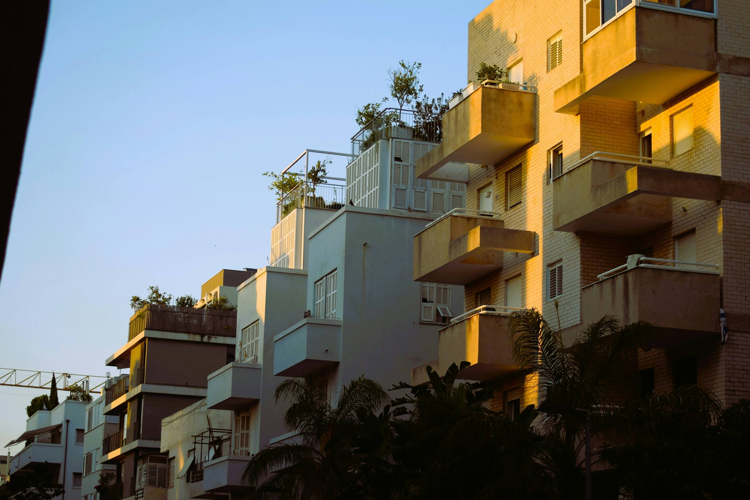 Apartment balconies with plants, against a clear sky