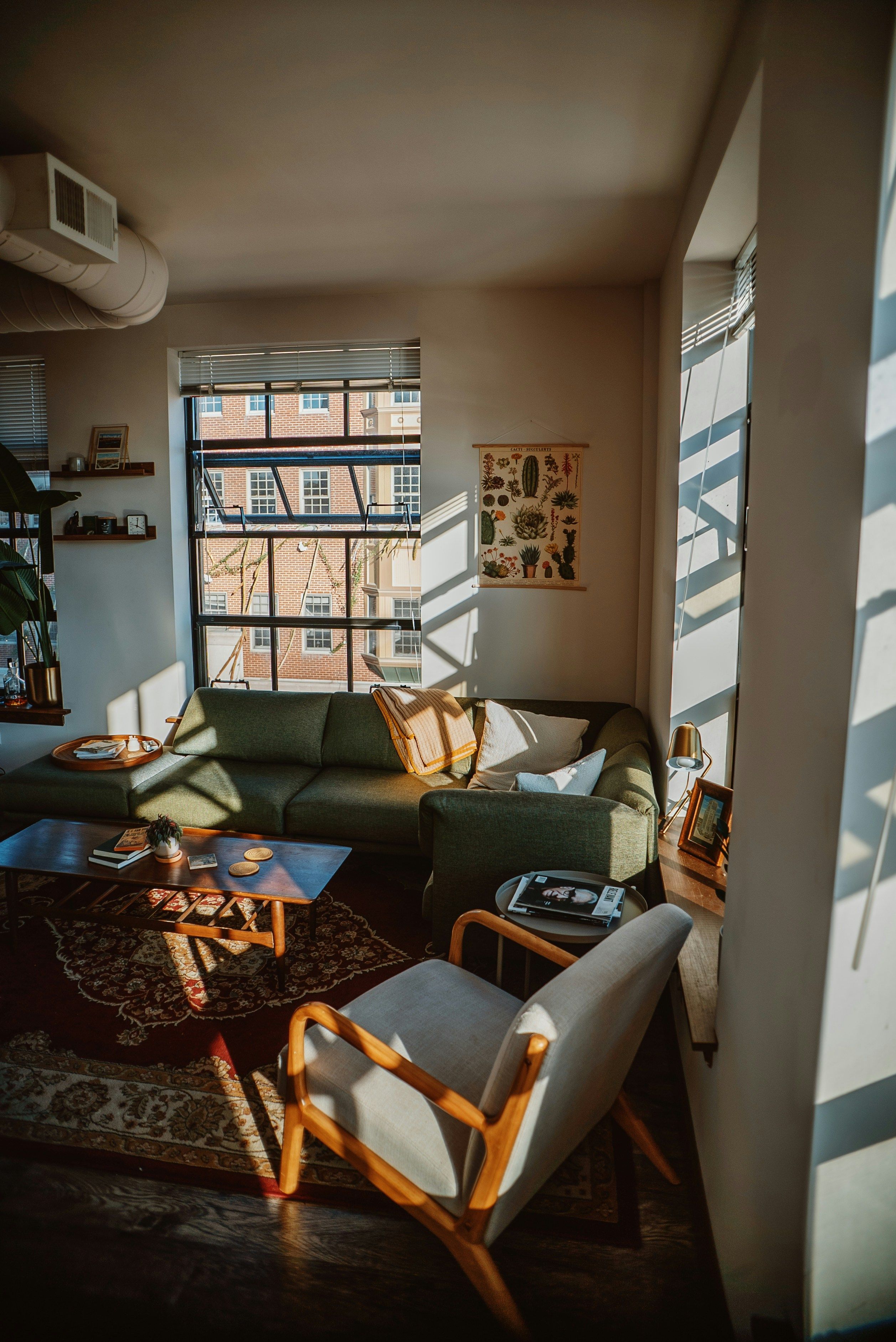 A living room with a sofa, an armchair and a patterned rug by the window