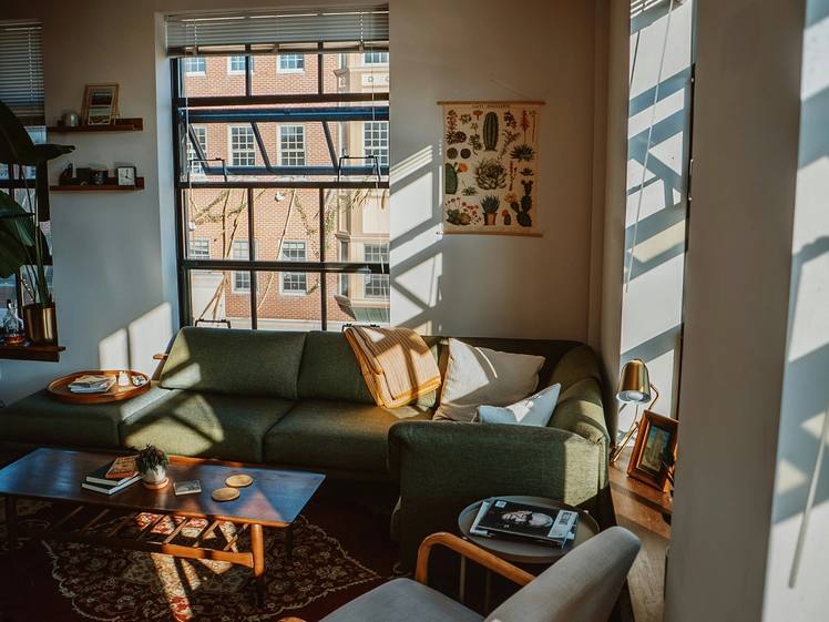 A living room with a sofa, an armchair and a patterned rug by the window