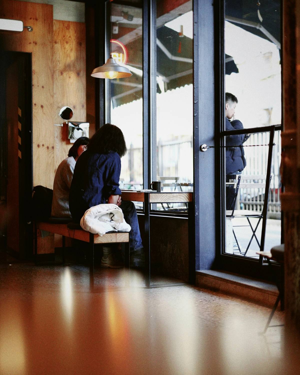 A bright room with wooden floors and tall windows onto a balcony