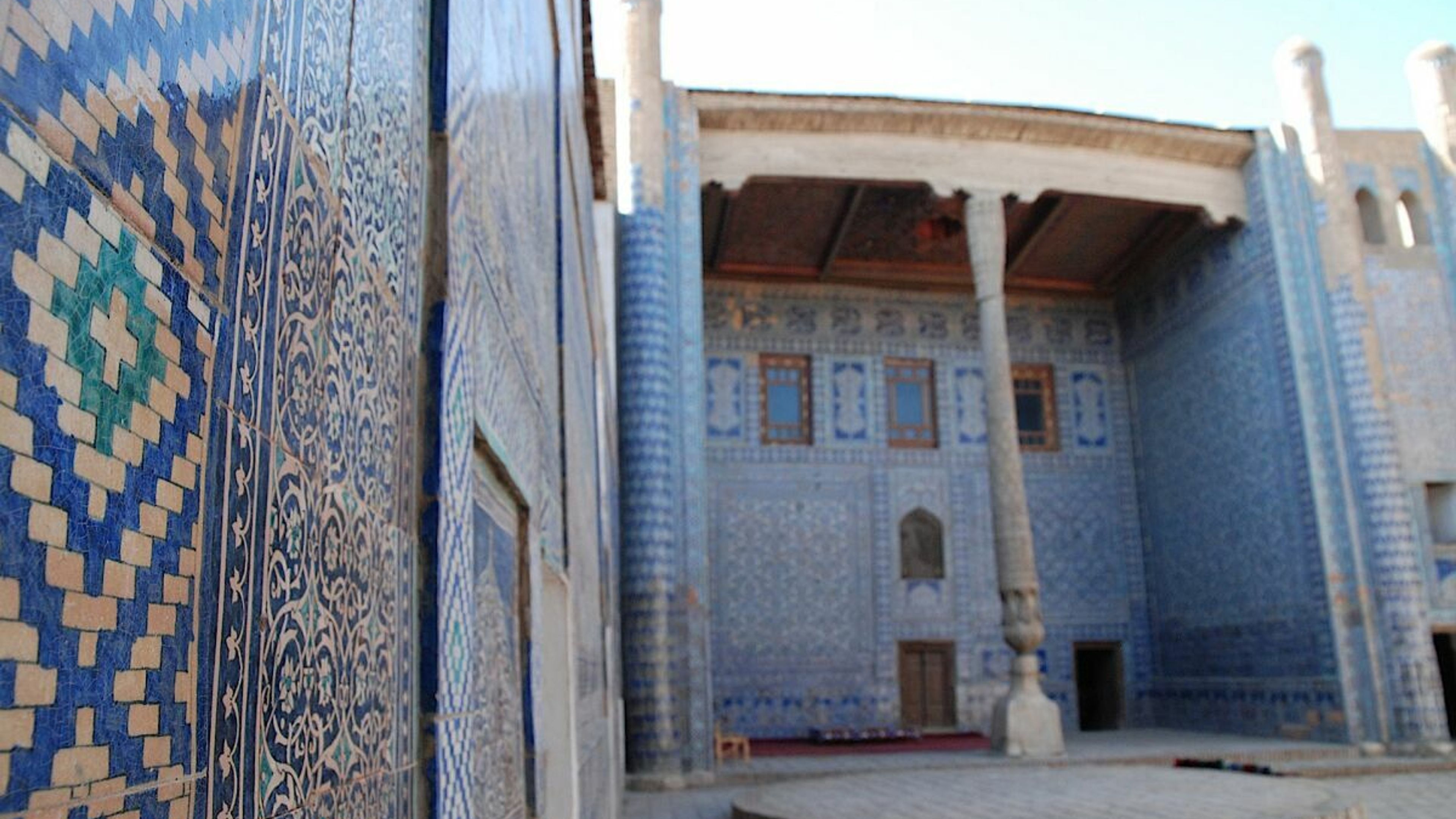 Harem nel Konya Ark a Khiva, Uzbekistan: Magnifico cortile con piastrelle a mosaico blu e colonne intagliate.