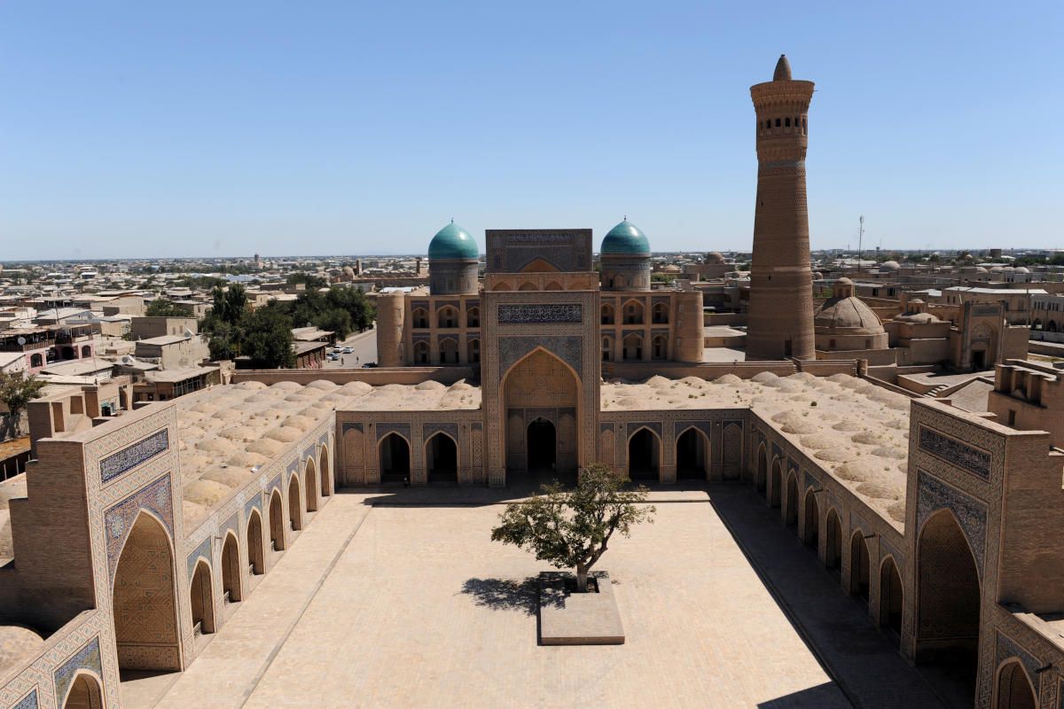 Blick in den Innenhof der Kalon Moschee in Buchara, Usbekistan, mit Minarett und blauen Kuppeln.