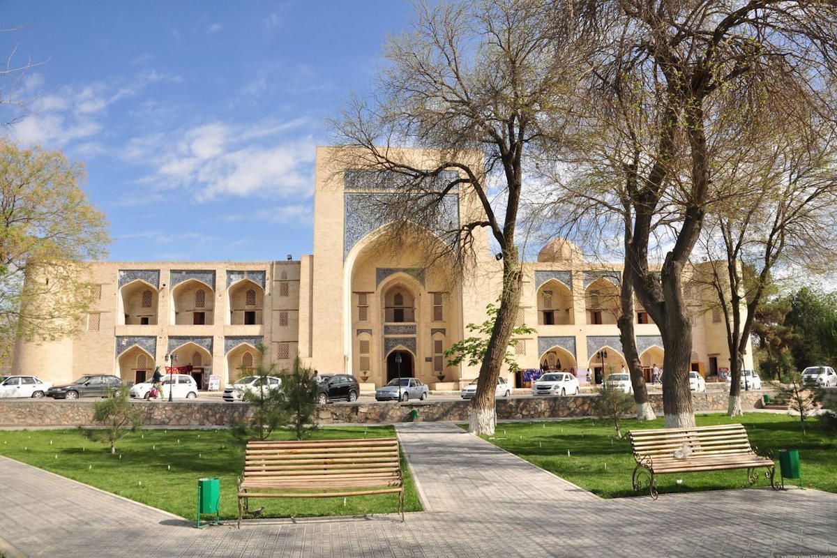 La madrasa historique Kukaldash à Boukhara, Ouzbékistan, avec un parc et des arbres, site touristique de l'UNESCO.
