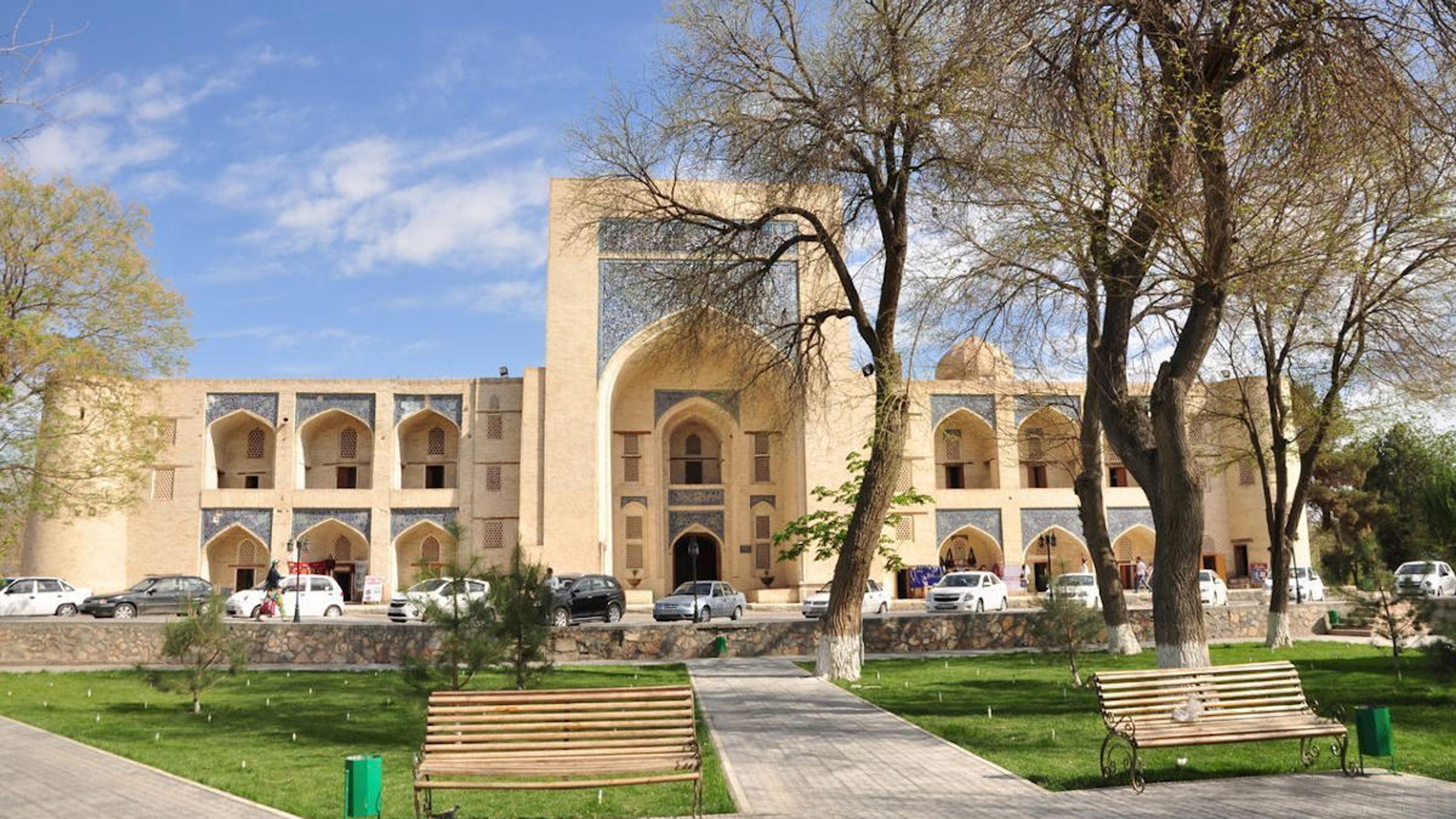 La madrasa historique Kukaldash à Boukhara, Ouzbékistan, avec un parc et des arbres, site touristique de l'UNESCO.