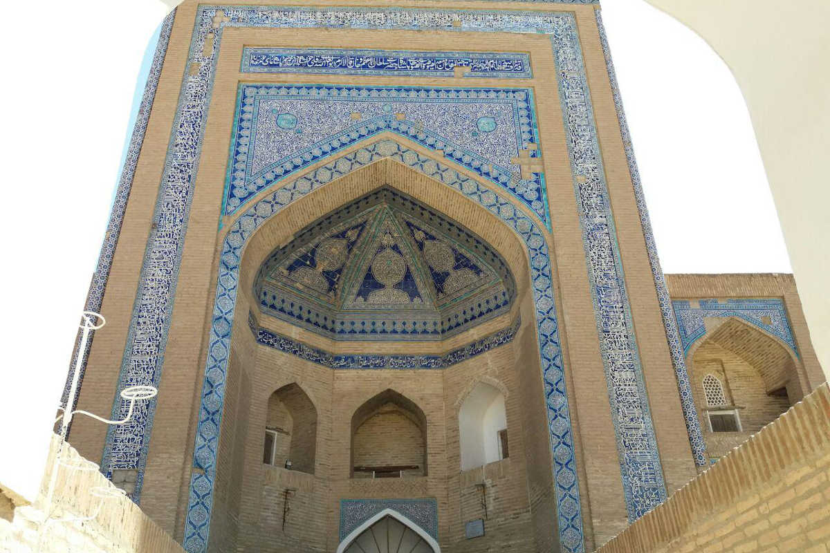 Facade of Abdullakhan Madrasa in Khiva, Uzbekistan, featuring intricate blue mosaics and Islamic architecture.