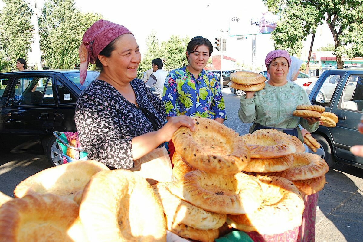 Usbekische Frauen verkaufen traditionelles Fladenbrot (Non) auf einem Straßenmarkt in Usbekistan.