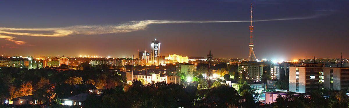 Vue de la ligne d'horizon illuminée de Tachkent la nuit avec tour de télécommunication et hôtels modernes.