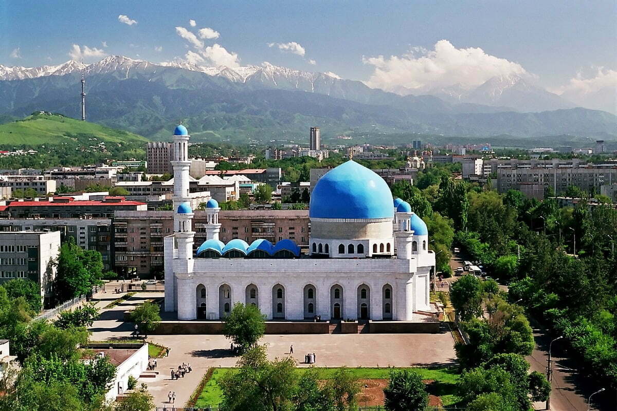 Zentralmoschee in Almaty, Kasachstan, mit blauen Kuppeln vor dem Panorama des Tian-Shan-Gebirges als Sehenswürdigkeit.