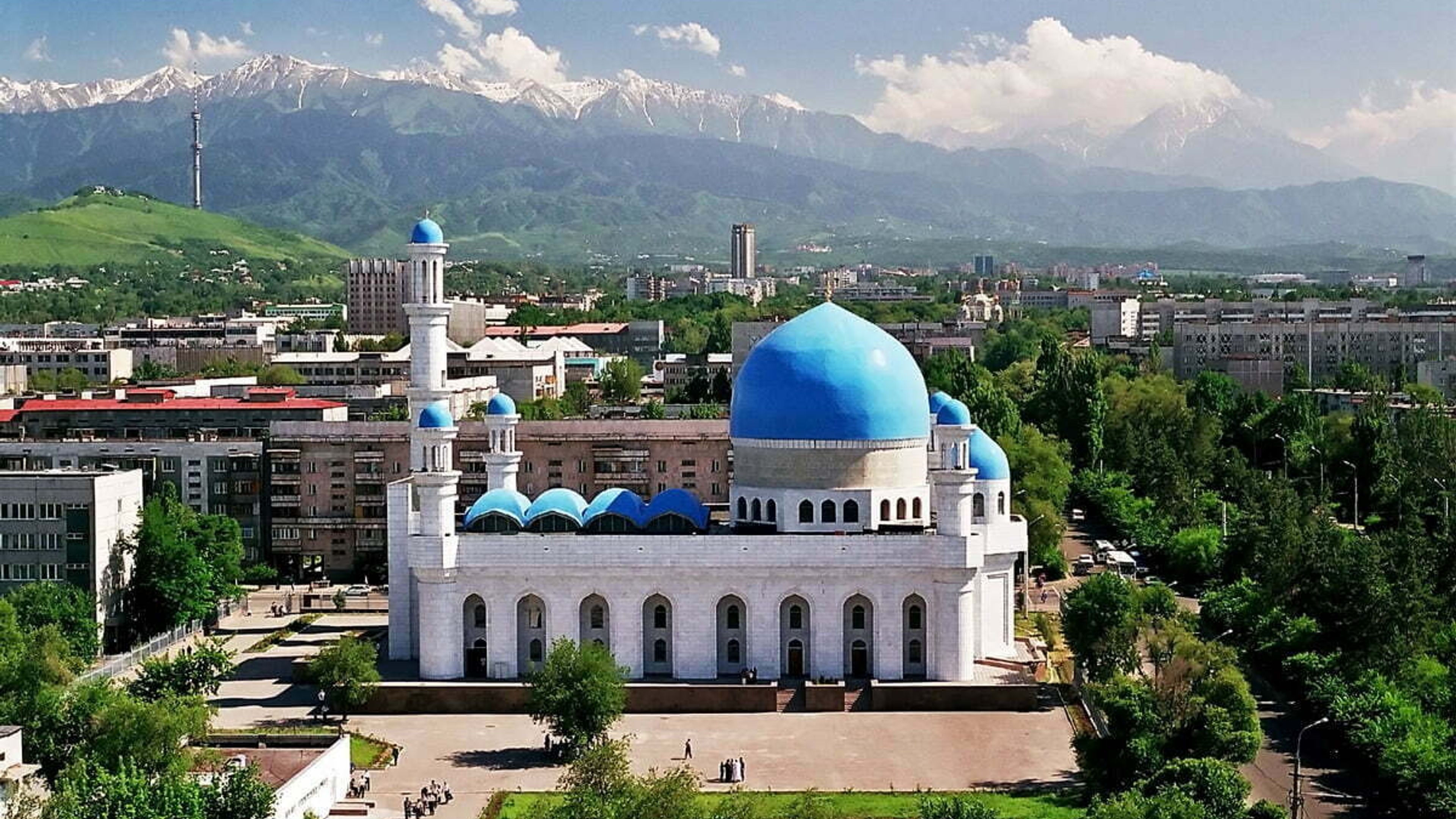 Zentralmoschee in Almaty, Kasachstan, mit blauen Kuppeln vor dem Panorama des Tian-Shan-Gebirges als Sehenswürdigkeit.