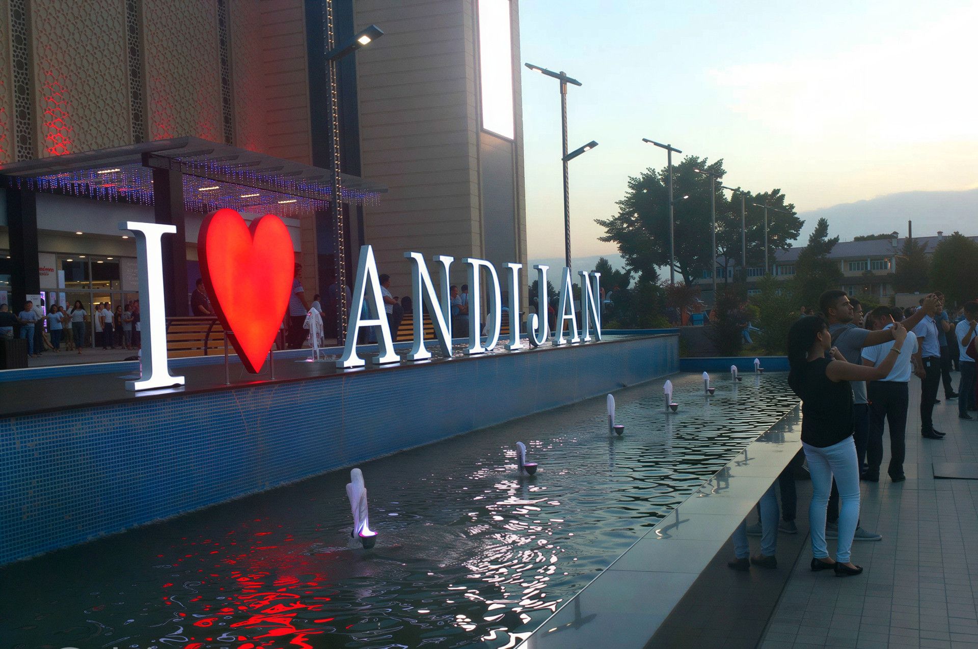 I Love Andidschan Schriftzug mit beleuchtetem Brunnen bei Nacht während einer Usbekistan Reise.