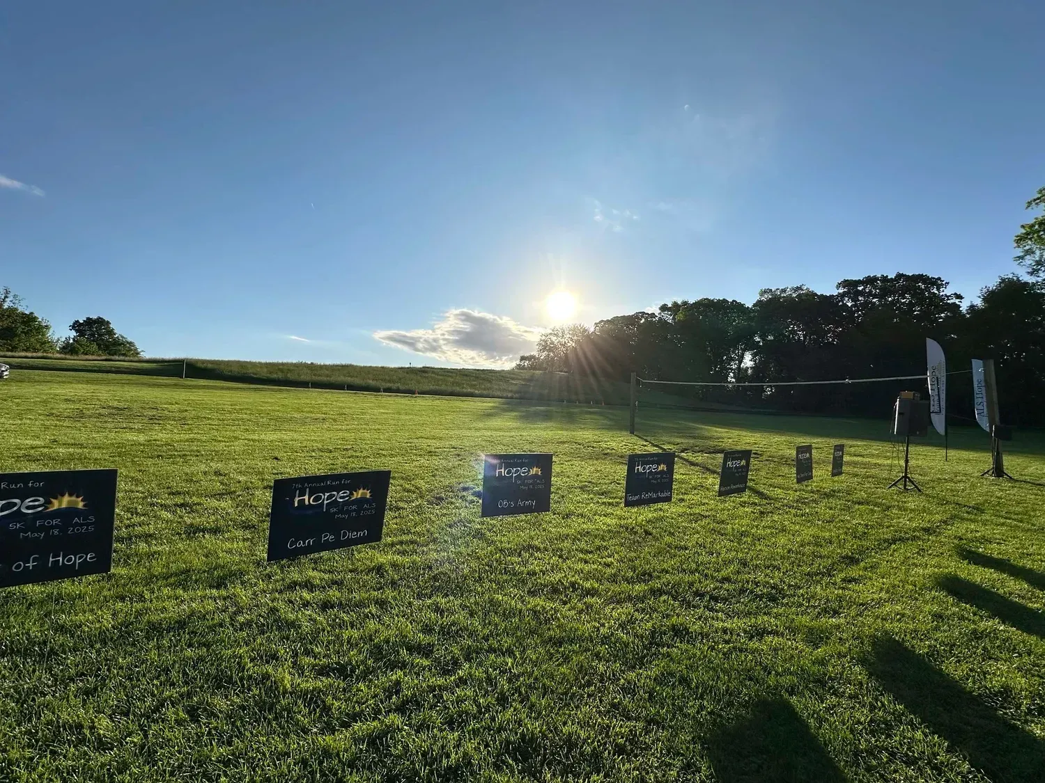 Sunrise over the course at the Run for Hope 5K, with team signs lining the field.