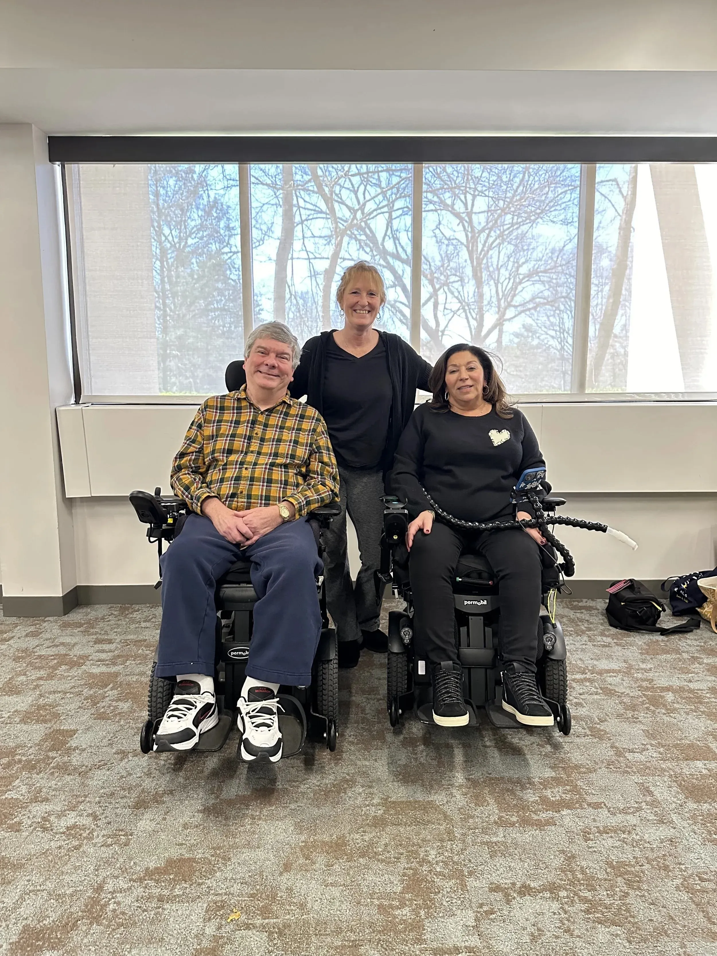 Two people who use power wheelchairs alongside a member of the care team at an ALS Hope Foundation gathering.