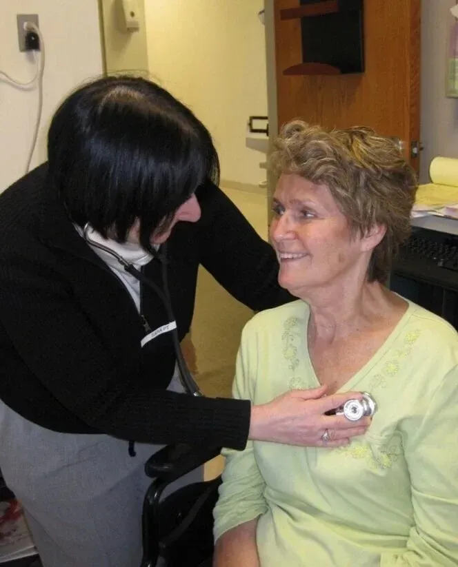A clinician listening to a patient's chest during a clinic appointment.