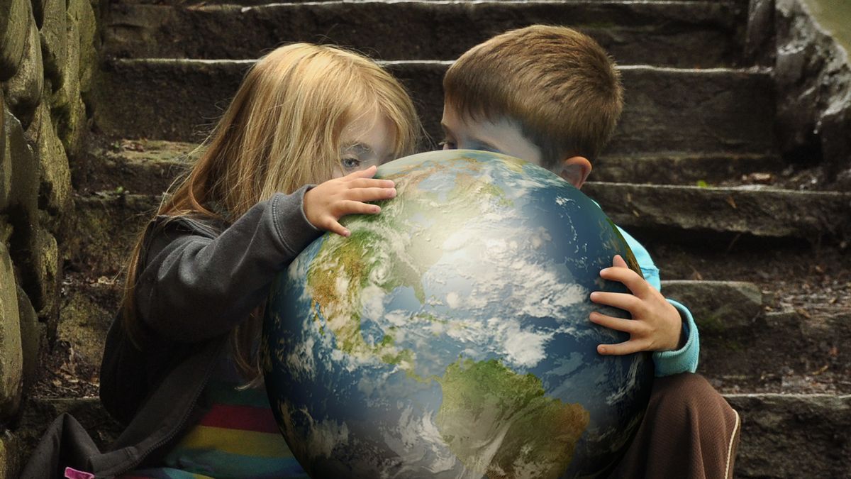 Two children studying a bright globe on a dark stairwell