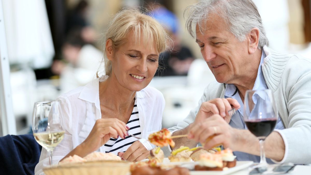 A senior couple sits down at an outdoor restaurant for healthy open air dining