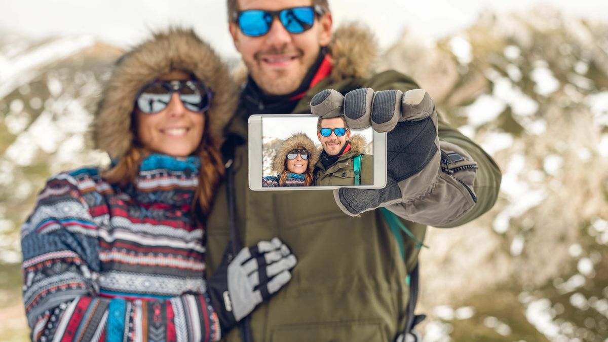 Couple takes a selfie outside in their winter coats while on vacation.