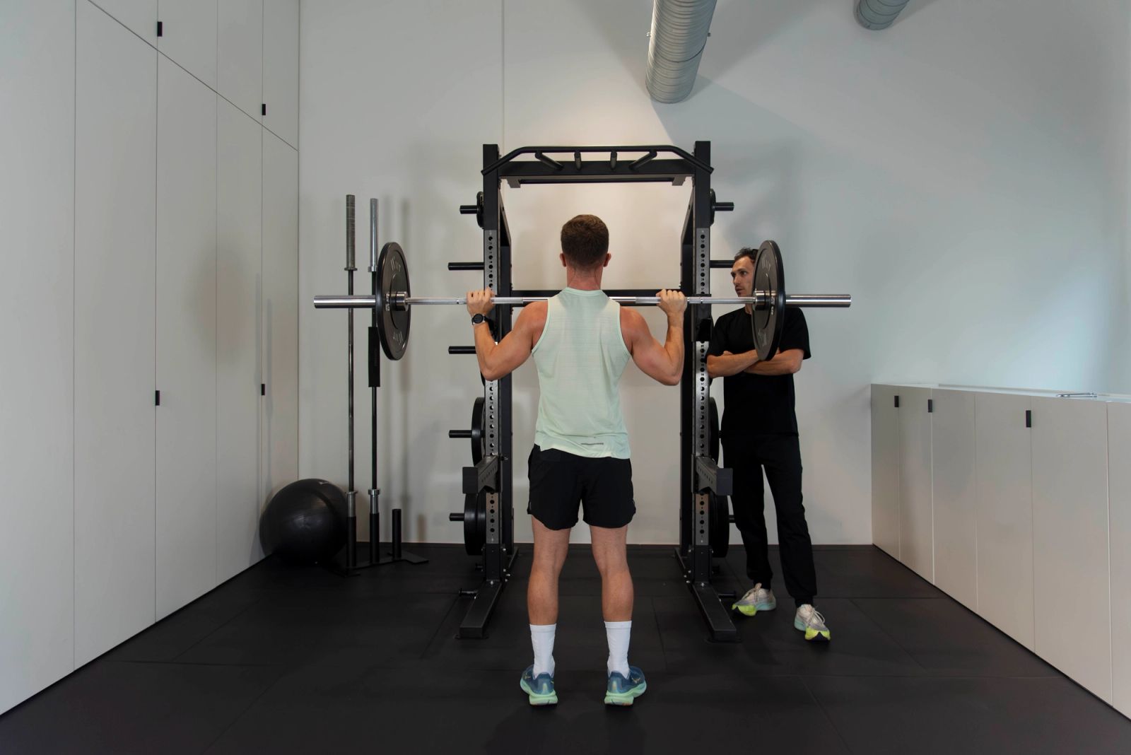 Sportif réalisant un exercice de renforcement à la poulie sous supervision