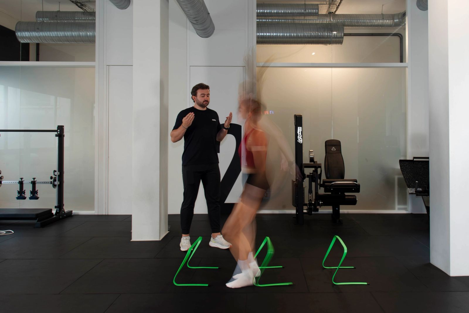 Sportive travaillant ses appuis sur le plateau technique avec un praticien CORE