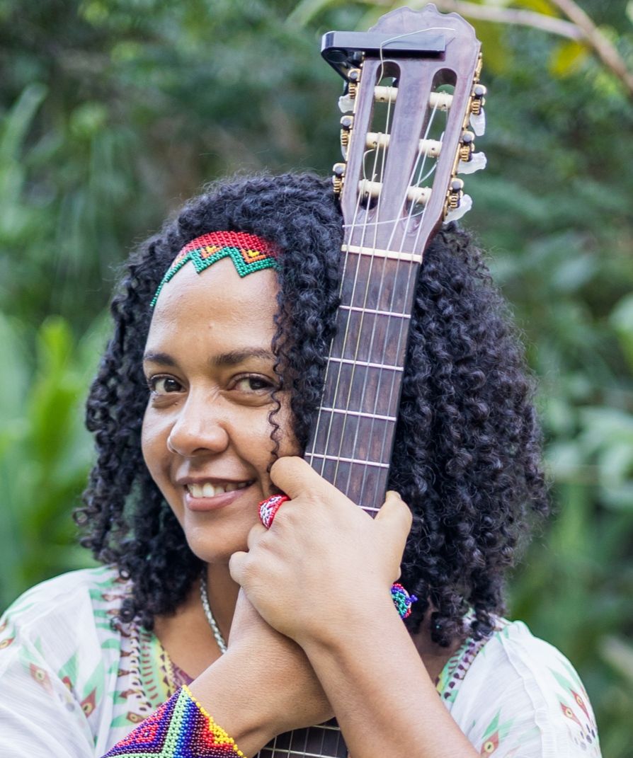 Andréa Sorrindo e abraçando o violão.