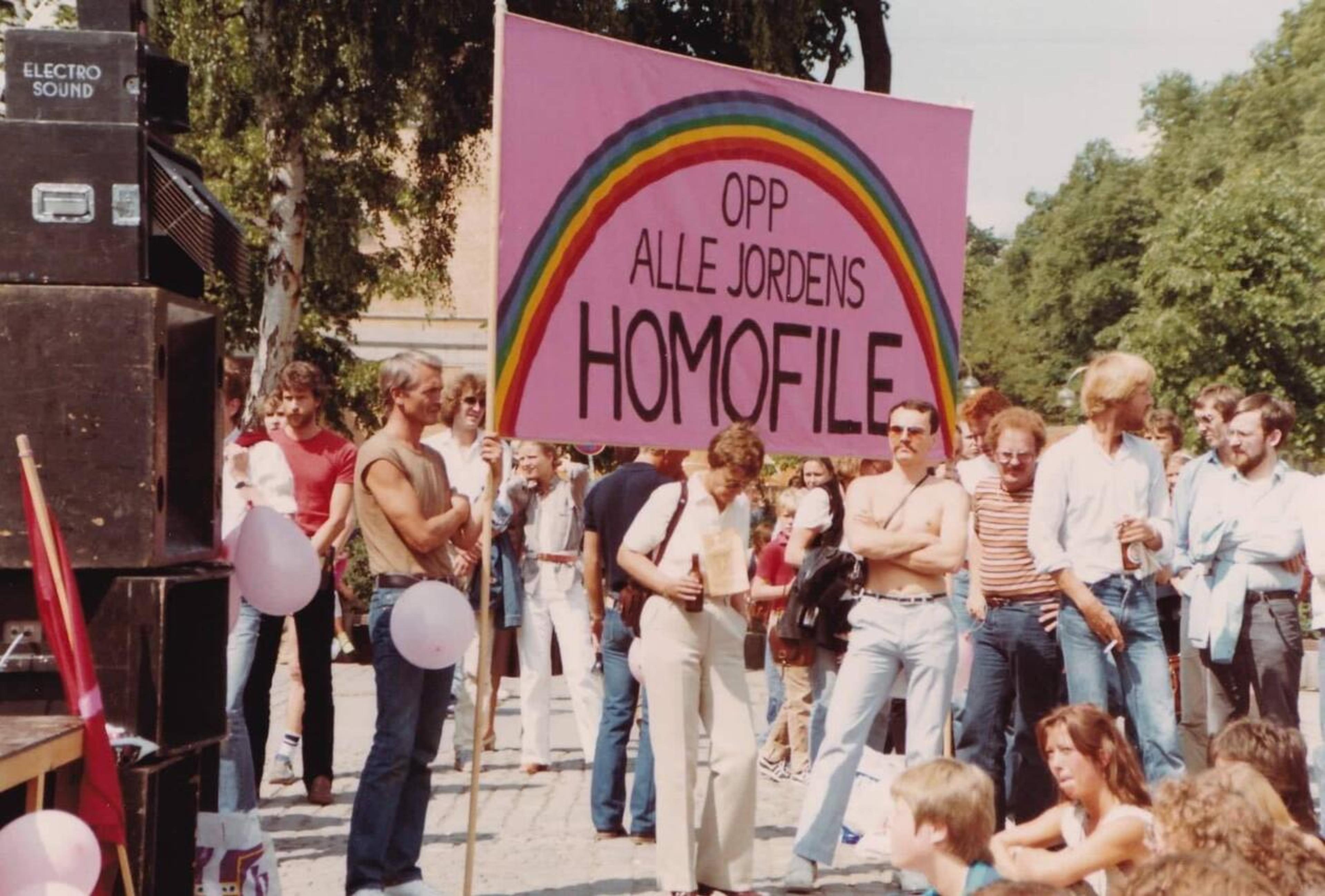En gruppe står med rosa banner og påskriften "Opp alle jordens homofile" under homomarsjen i Oslo i 1982