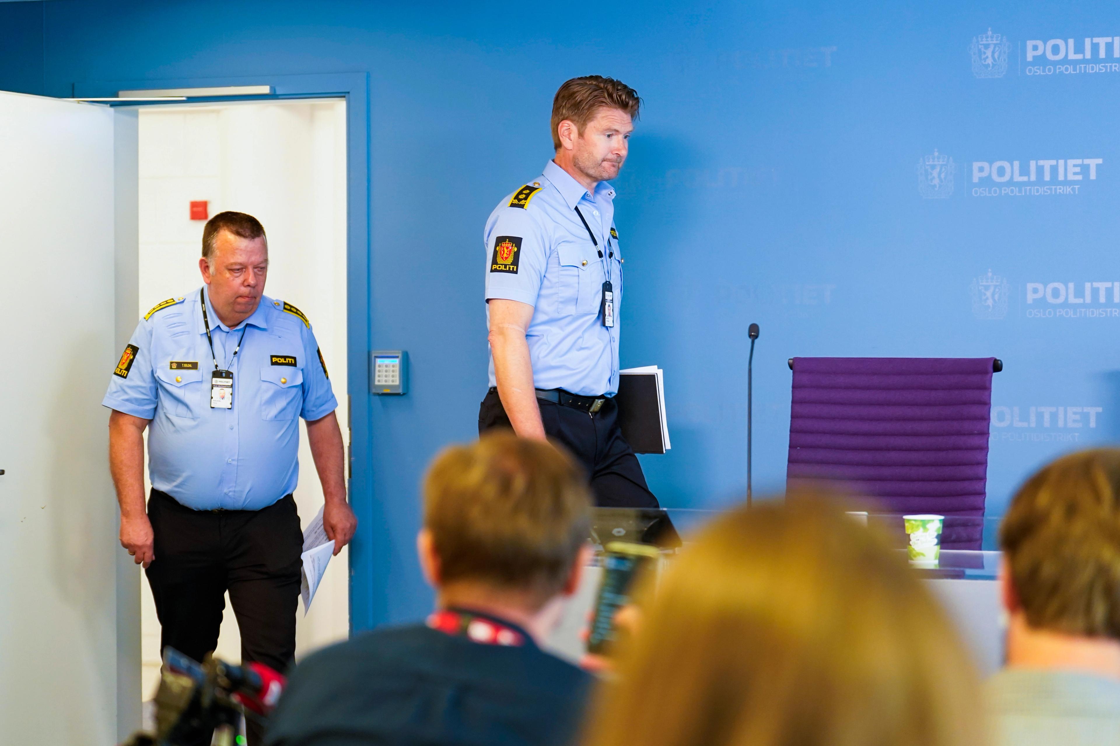 To politimenn går opp på et podium foran en forsamling journalister.