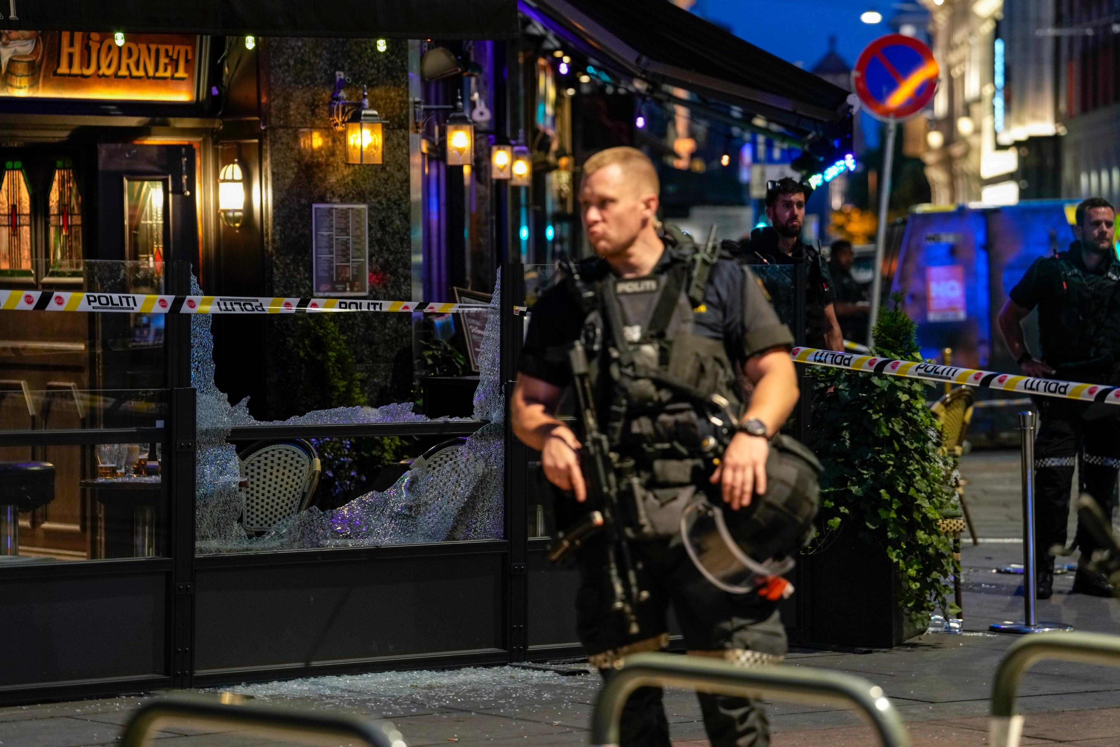 En bevæpnet politimann holder vakt utenfor Per på hjørnet. I bakgrunnen ses sperrebånd, og et vindu mot uteserveringen er knust.